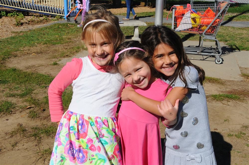 3 girls on playground with arms around each other