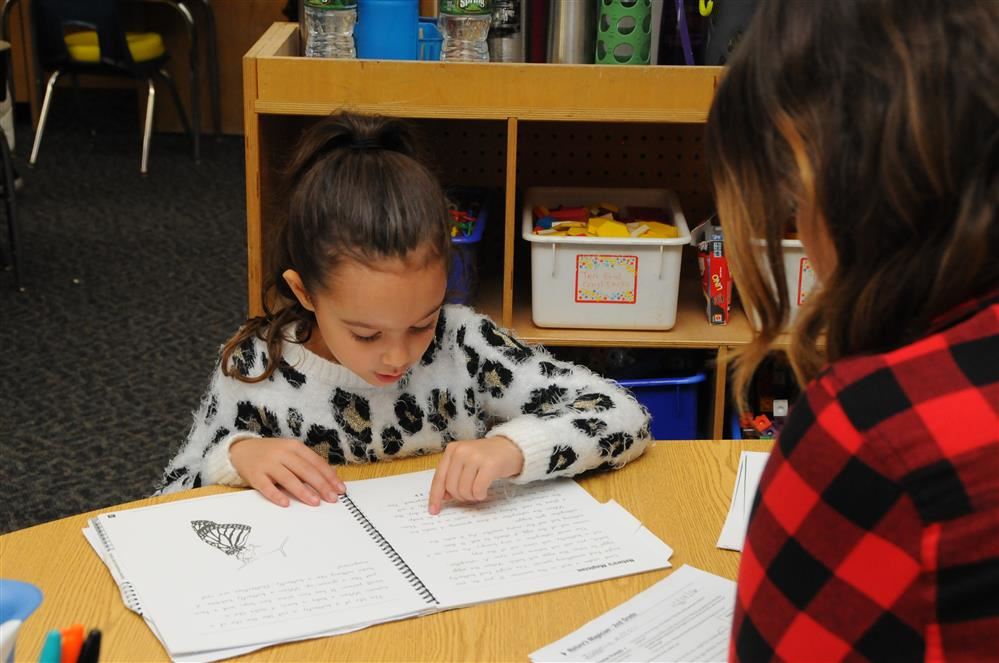 girl reading to teacher