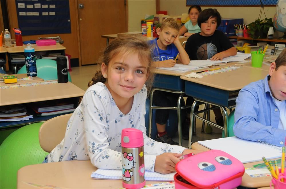 THIRD GRADER SMILING AT DESK
