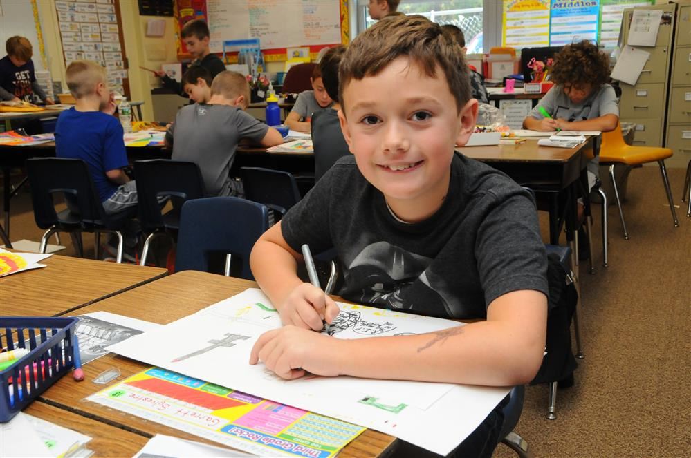 BOY at desk writing in notebook