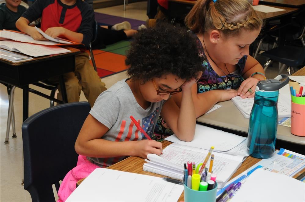 2 girls writing in notebook