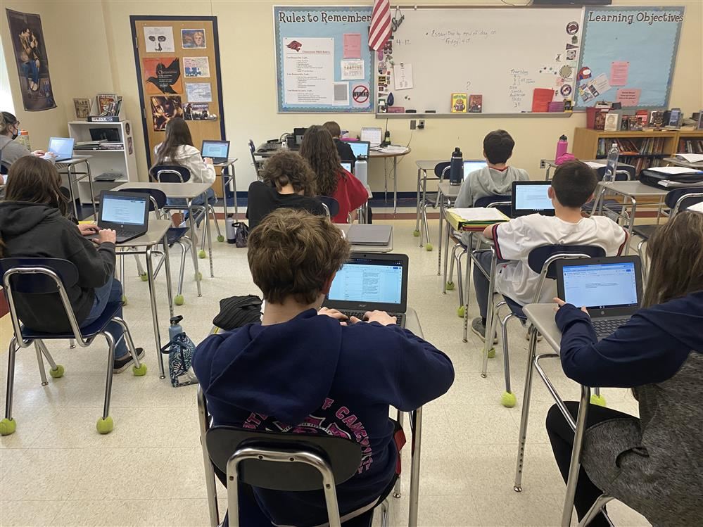 teacher helping students on computers